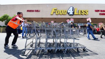 A grocery store worker pushes shopping carts as fellow workers, represented by the United Food and Commercial Workers International Union (UFCW), hold a boycott rally in front of a Food4Less Supermarket in Los Angeles, California on May 12, 2021, protesting alleged lack of progress on contract negotiations which began in January. - US job openings reached a record 8.1 million in March but businesses are struggling to find enough workers. (Photo by Frederic J. BROWN / AFP) (Photo by FREDERIC J. BROWN/AFP via Getty Images)