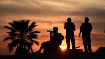 People view the sun set as a child drinks from a water bottle on June 15, 2021 in Los Angeles, California as temperatures soar in an early-season heatwave. (Photo by Frederic J. BROWN / AFP) (Photo by FREDERIC J. BROWN/AFP via Getty Images)