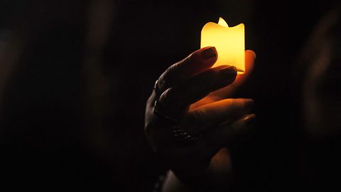 A woman holds a candle during a demonstration against the Russian invasion in Ukraine outside the Russian Embassy in Uruguay in Montevideo, on March 2, 2022. (Photo by PABLO PORCIUNCULA / AFP) (Photo by PABLO PORCIUNCULA/AFP via Getty Images)