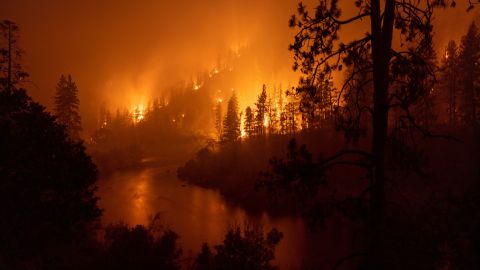 TOPSHOT - Flames burn to the Klamath River during the McKinney Fire in the Klamath National Forest northwest of Yreka, California, on July 31, 2022. - The largest fire in California this year is forcing thousands of people to evacuate as it destroys homes and rips through the state's dry terrain, whipped up by strong winds and lightning storms. The McKinney Fire was zero percent contained, CalFire said, spreading more than 51,000 acres near the city of Yreka. (Photo by DAVID MCNEW / AFP) (Photo by DAVID MCNEW/AFP via Getty Images)