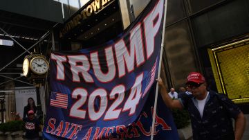 La gente sostiene una pancarta que dice "Trump 2024" fuera del edificio Trump Tower en Nueva York.