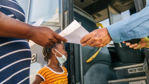 Una mujer migrante recibe su boleto antes de abordar un autobús Greyhound en Texas.