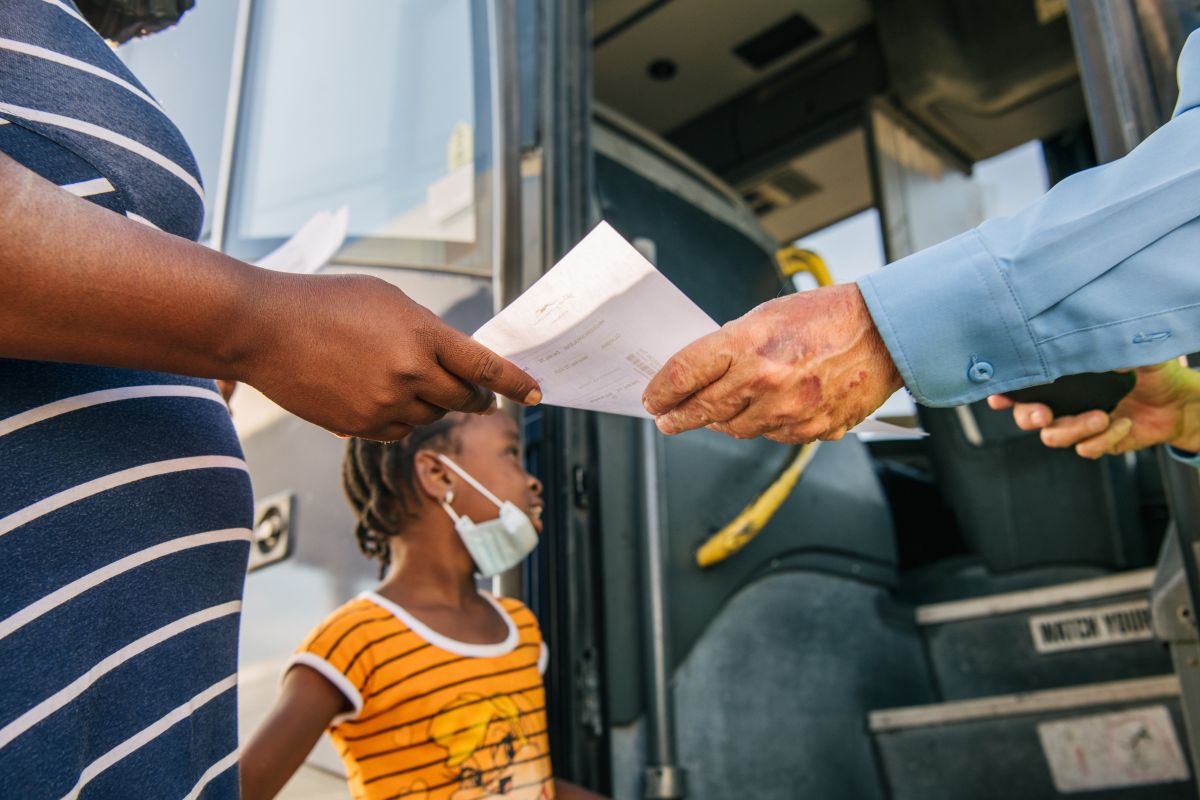 Una mujer migrante recibe su boleto antes de abordar un autobús Greyhound en Texas.