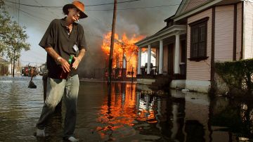 Un residente pasa junto a un incendio en una casa en llamas en el distrito 7 el 6 de septiembre de 2005 en Nueva Orleans, Luisiana.