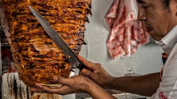 (FILES) In this file photo taken on October 31, 2016, chef Adrian Reyes cuts small slices of marinated thin fillets of pork already cooked from "the ball" or "the spinning top", to make traditional "Tacos al Pastor" (shepherd- style tacos) at El Tizoncito restaurant in Mexico City. / AFP PHOTO / OMAR TORRES / TO GO WITH AFP STORY by Jean Luis ARCE / More pictures in AFP FORUM (Photo credit should read OMAR TORRES/AFP via Getty Images)