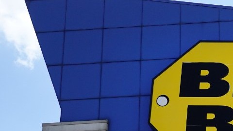 Fachada de una tienda Best Buy con un letrero amarillo fijado al muro.