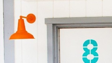 Imagen de la entrada de un motel con una silla de color azul y una bicicleta en el frente.