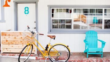 Imagen de la entrada de un motel con una silla de color azul y una bicicleta en el frente.