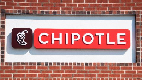 Fachada de una pared con ladrillos rojos en el que se ve un letrero del restaurante Chipotle.