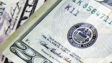 Un birrete de color negro sobre varios billetes de $100 dólares.