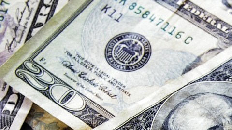 Un birrete de color negro sobre varios billetes de $100 dólares.