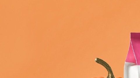 Imagen de una bolsa de galletas de colores blanco, naranja y rosa, frente a un grupo de galletas, cuatro donas apiladas y una calabaza.