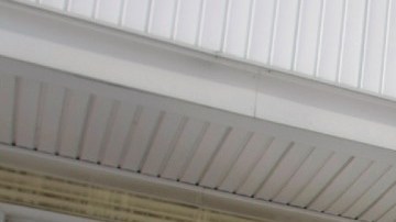 El letrero de venta en colores azul, blanco y rojo se ve frente a una casa de colores claros.