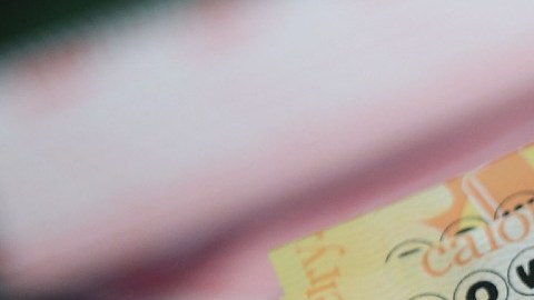 Una persona sostiene varios boletos de Powerball con las manos.