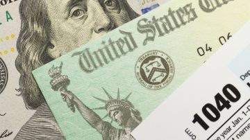 Imagen de un cheque de reembolso, un formulario del IRS y un billete de dólar.