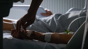 Una persona atiende a un paciente en una cama de hospital.