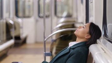 Una mujer se recarga en las bancas de un vagón de metro.
