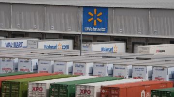 Imagen de un logotipo de la cadena Walmart, en medio de un parque de camiones de carga y cajas de tráiler.