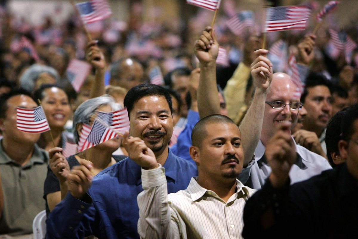 Inmigrantes agitan banderas tras jurar como ciudadanos estadounidenses en ceremonias de naturalización.