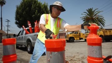 MAYWOOD, CA - JUNE 23: Ernest Beas, an employee of ICE Engineering, picks up traffic control posts after completing a speed bump construction project that was contracted out by the city of Maywood on June 23, 2010 in Maywood, California. Facing a $450,000 budget deficit, the Maywood City Council approved the most drastic action yet of any California city to wrest control of its fiscal crisis by firing all its employees, disbanding its police department and contracting out its entire municipal operations to a neighboring city. County sheriffs will replace Maywood police officers but council members will remain on the payroll to set policy. (Photo by David McNew/Getty Images)