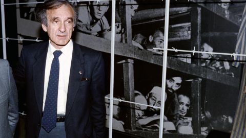 El escritor y ganador del premio Nobel de la Paz de 1986, Elie Wiesel (izquierda), se para frente a una foto suya (esquina inferior derecha) y otros reclusos, tomada en el campo de concentración de Buchenwald en 1945, durante su visita al Holocausto el 18 de diciembre de 1986.