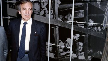 El escritor y ganador del premio Nobel de la Paz de 1986, Elie Wiesel (izquierda), se para frente a una foto suya (esquina inferior derecha) y otros reclusos, tomada en el campo de concentración de Buchenwald en 1945, durante su visita al Holocausto el 18 de diciembre de 1986.