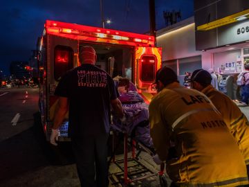 TOPSHOT - Paramedics of the LAFD Station No9 wear a face mask as a preventive measure against the spread of the COVID-19 novel coronavirus from a homeless woman who had seizures on the street at Skid Row, before boarding her in the ambulance to go to a hospital on April 12, 2020 in downtown Los Angeles, California. - One of the busiest fire station in the country , LA Fire Station 9 is on the front lines of California's homeless crisis e Coronavirus pandemic. (Photo by Apu GOMES / AFP) (Photo by APU GOMES/AFP via Getty Images)
