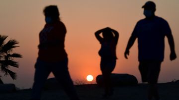 The sun sets behind people walking an afternoon hike in Los Angeles, California on July 12, 2021. - Wildfires were burning across more than one million acres of the western United States and Canada on July 12, 2021, as scorching temperatures held their grip on areas reeling from a brutal weekend heat wave. (Photo by Frederic J. BROWN / AFP) (Photo by FREDERIC J. BROWN/AFP via Getty Images)