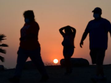 The sun sets behind people walking an afternoon hike in Los Angeles, California on July 12, 2021. - Wildfires were burning across more than one million acres of the western United States and Canada on July 12, 2021, as scorching temperatures held their grip on areas reeling from a brutal weekend heat wave. (Photo by Frederic J. BROWN / AFP) (Photo by FREDERIC J. BROWN/AFP via Getty Images)