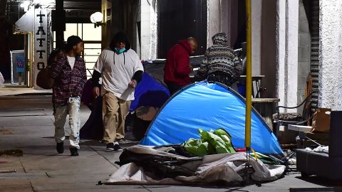 Pedestrians walk past tents housing the homeless on the streets of Los Angeles, California on February 24, 2022, as volunteers participate on the third night of the Greater Los Angeles Homeless Count on February 24, 2022 in Los Angeles, California. - he annual count in a city with one of the largest homeless communities in the country is done to obtain an accurate count of unhoused people across Los Angeles County. (Photo by Frederic J. BROWN / AFP) (Photo by FREDERIC J. BROWN/AFP via Getty Images)