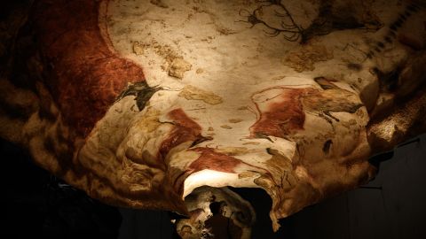 Un visitante observa una sección de la réplica de tamaño natural de la cueva de Lascaux después de una visita especial a la luz de las antorchas el 16 de junio de 2022 en Montignac.