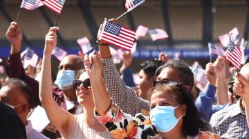 Nuevos ciudadanos ondean banderas tras prestar juramento en una ceremonia de naturalización en Los Ángeles.
