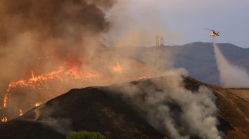 CASTAIC, CALIFORNIA - AUGUST 31: A firefighting helicopter performs a water drop as the Route Fire burns on August 31, 2022 near Castaic, California. Evacuations have been ordered as the brush fire has scorched more than 4,600 acres and closed down the 5 freeway at the start of a brutal heat wave in Southern California. The National Weather Service issued an Excessive Heat Warning for most of Southern California through Labor Day. Climate models almost unanimously predict that heat waves will become more intense and frequent as the planet continues to warm. (Photo by Mario Tama/Getty Images)