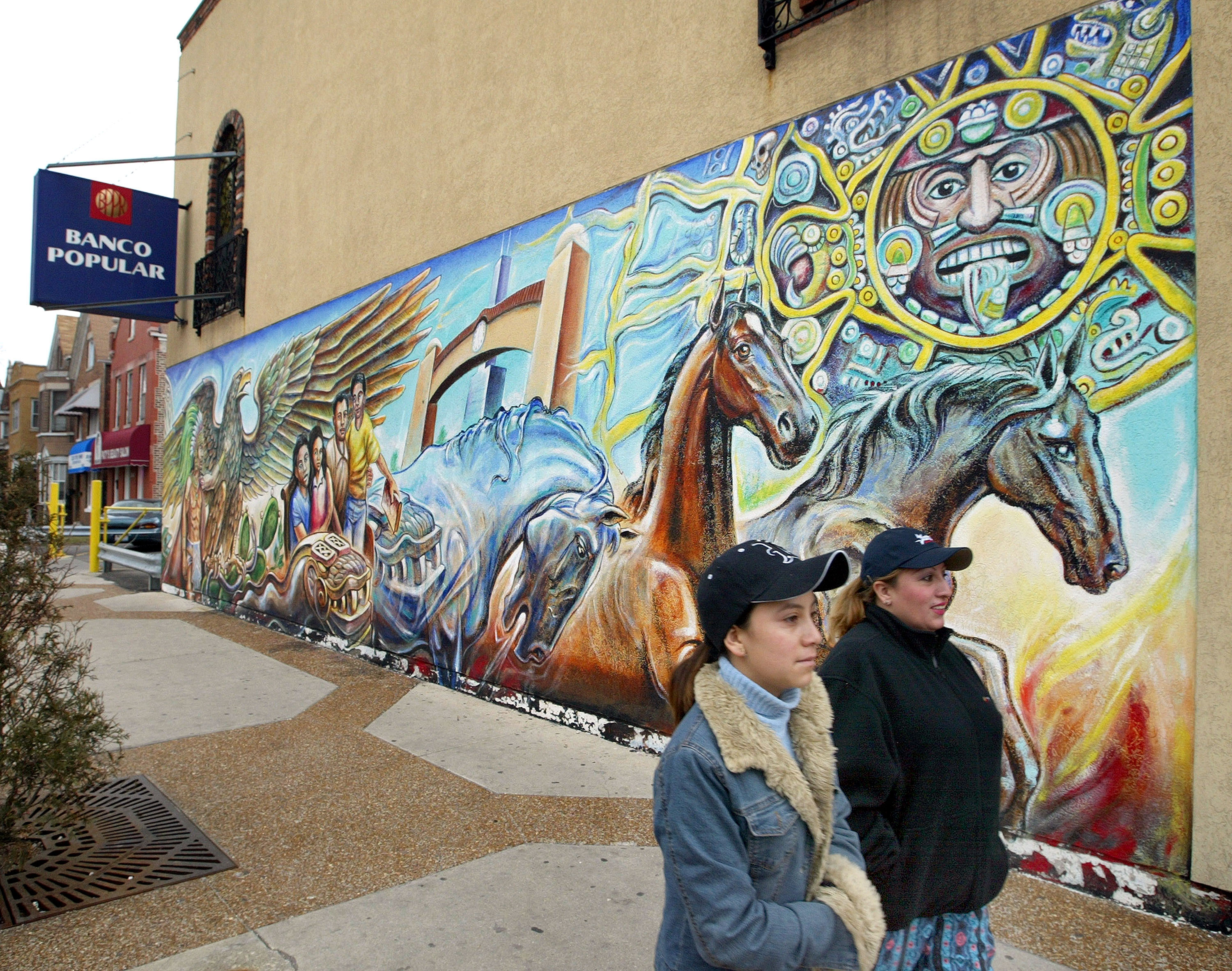 Dos mujeres pasan ante un mural en el vecindario hispano "La Villita" en Chicago.