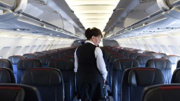 American Airlines longest serving flight attendant, Bette Nash (R), 81 years old, checks the passengers' seats for forgotten items before disembarking from her daily return flight to Boston at Ronald Reagan Washington Airport in Arlington, Virginia on December 19, 2017. American Airlines Flight 2160 from Boston has just arrived in Washington, D.C., and Bette Nash, 81, helps the passengers disembark. After six decades crossing the skies as a flight attendant, Nash still has impeccable style, incredible energy and a constant smile. In the United States, pilots must retired at 65 but there is no such restriction on commercial flight attendants, of which Bette Nash is probably the world's most senior. / AFP PHOTO / Eric BARADAT (Photo credit should read ERIC BARADAT/AFP via Getty Images)