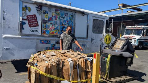 Un vendedor de helados muestra hasta donde llegaron las cenizas que comenzaban a incendiar las pacas de cartón. (Jacqueline García/La Opinión)