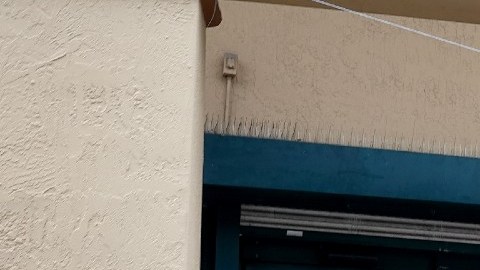 Una mujer entra a una tienda en donde cuelga una lona de color rojo en la que se anuncia contratación.