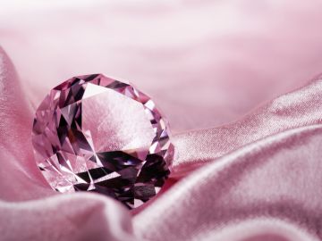 Imagen de un diamante de color rosa sobre una tela satinada en color rosa.
