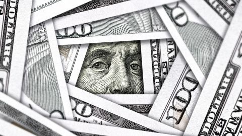 Imagen de varios billetes sobrepuestos en otro de $100 dólares.