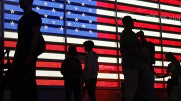 Imagen de una bandera de los Estados Unidos y las siluetas de varias personas.