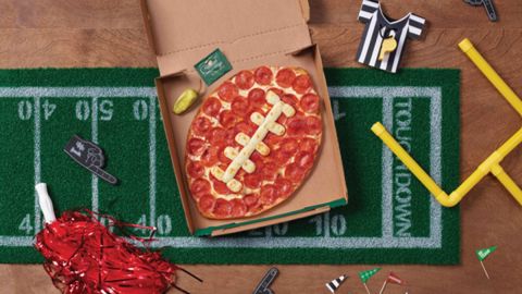 Imagen de una pizza en forma de balón de futbol americano en una caja de cartón.