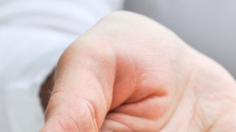 Una persona muestra con su mano unas llaves y con la otra sostiene una casa en miniatura.