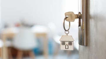 Imagen de unas llaves dentro de una chapa en la puerta abierta de una vivienda.