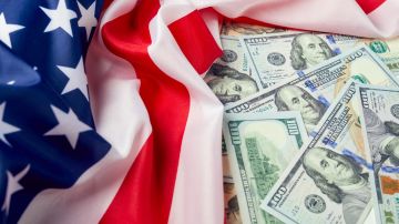 Imagen de una bandera de Estados Unidos junto con varios billetes de $100 dólares.