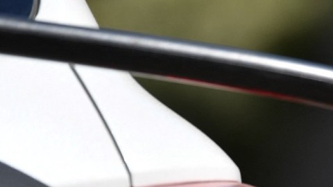 Imagen de una persona que sostiene una pistola despachadora de gasolina mientras surte combustible en un vehículo blanco.