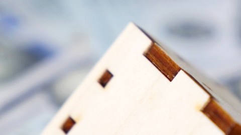 Imagen de una vivienda miniatura de madera y unas llaves sobre varias réplicas de billetes.
