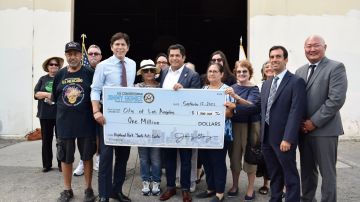 El congresista Jimmy Gómez (c) entrega el cheque a la comunidad de Highland Park, incluyendo al concejal Kervin de León (i).