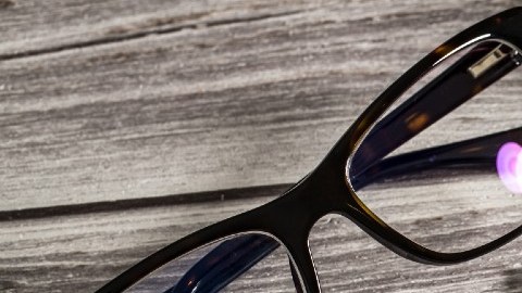 Una imagen en la que se ve un documento con un puntaje de crédito, el teclado de una computadora, unas gafas y una pluma.