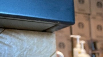 Imagen de un vaso con café de Starbucks, sobre una mesa de madera y en el fondo una persona que prepara café.