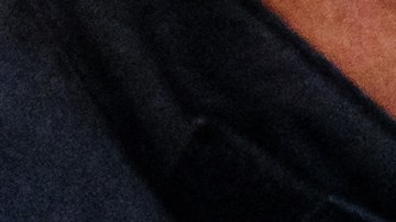 Defendant Rabieh R (R) covers his face as a judicial officer opens his handcuffs in the courtroom of the Higher Regional Court in Dresden, eastern Germany on August 30, 2022 prior to a hearing in the trial over a jewellery heist on the Green Vault (Gruenes Gewoelbe) museum in Dresden's Royal Palace in November 2019. - Six members of a notorious criminal gang stand trial in Germany over the spectacular heist in which 18th-century jewels were snatched from the state museum in Dresden. They are accused of gang robbery and arson after the brazen night raid on The Green Vault museum on November 25, 2019. (Photo by JENS SCHLUETER / POOL / AFP) (Photo by JENS SCHLUETER/POOL/AFP via Getty Images)